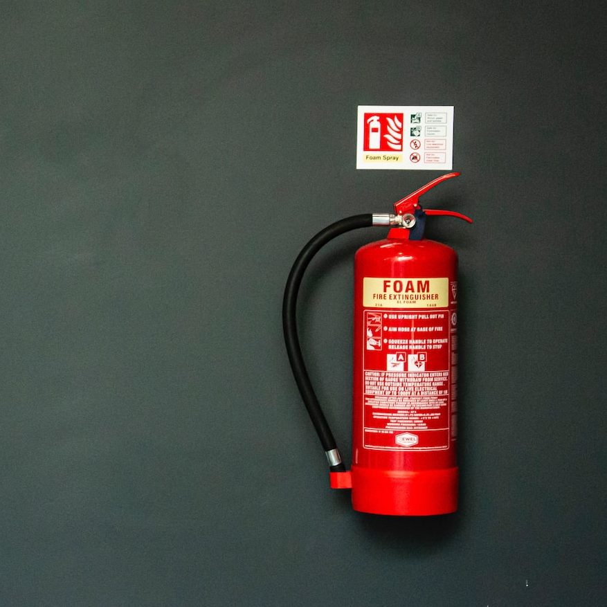 red fire extinguisher on gray wall